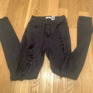 Vibrant black skinny jeans. Size 24. Large and small rips up both legs